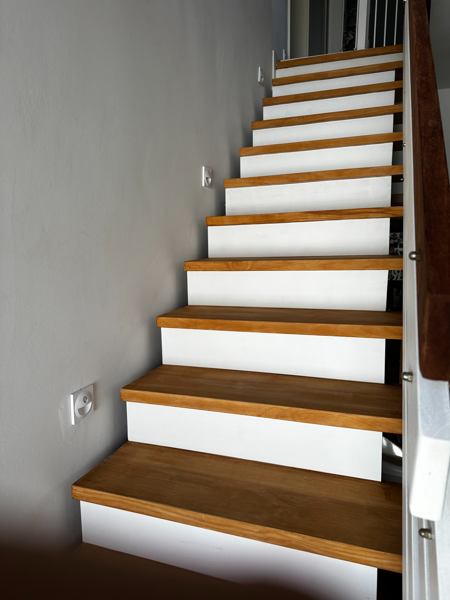 Massivholztreppe in Eiche mit weiß abgesetzten Setzstufen und dunklem Handlauf.